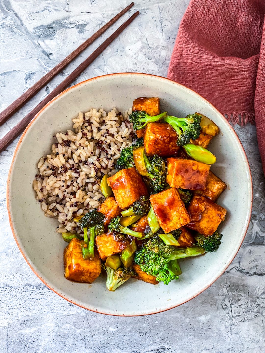 Large bowl of tofu with broccoli with a rich hoisin sauce and served with a quinoa rice mix.