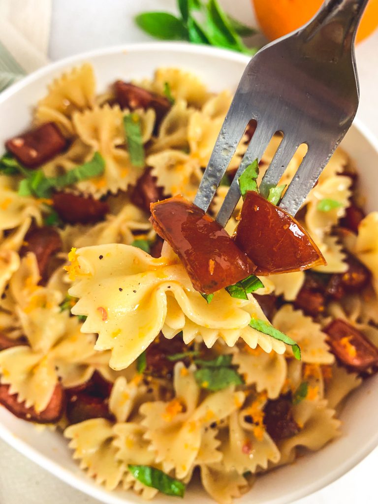 Fork digging into a fresh summertime pasta with a no-cook sauce made from tomatoes, basil, and orange zest.