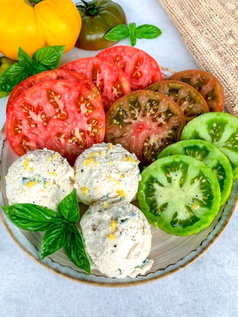 Platter with multicolored fresh heirloom tomatoes, basil, and a vegan tofu ricotta.