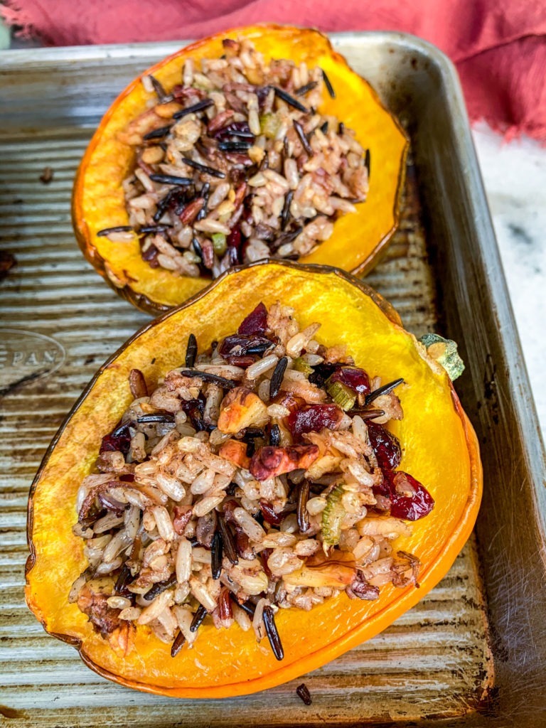 Vegan wild rice pilaf with toasted walnuts, and cranberries stuffed inside a roasted acorn squash.