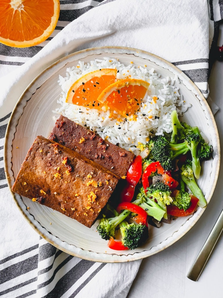 Savory orange ginger baked tofu cutlets served with rice and stir-fried vegetables.