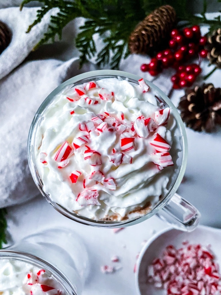 Overhead view of vegan hot chocolate topped with coconut whipped cream and crushed candy canes.