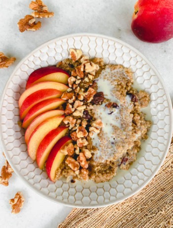 A warm breakfast cereal made from quinoa and garnished with fresh peaches and toasted walnuts.