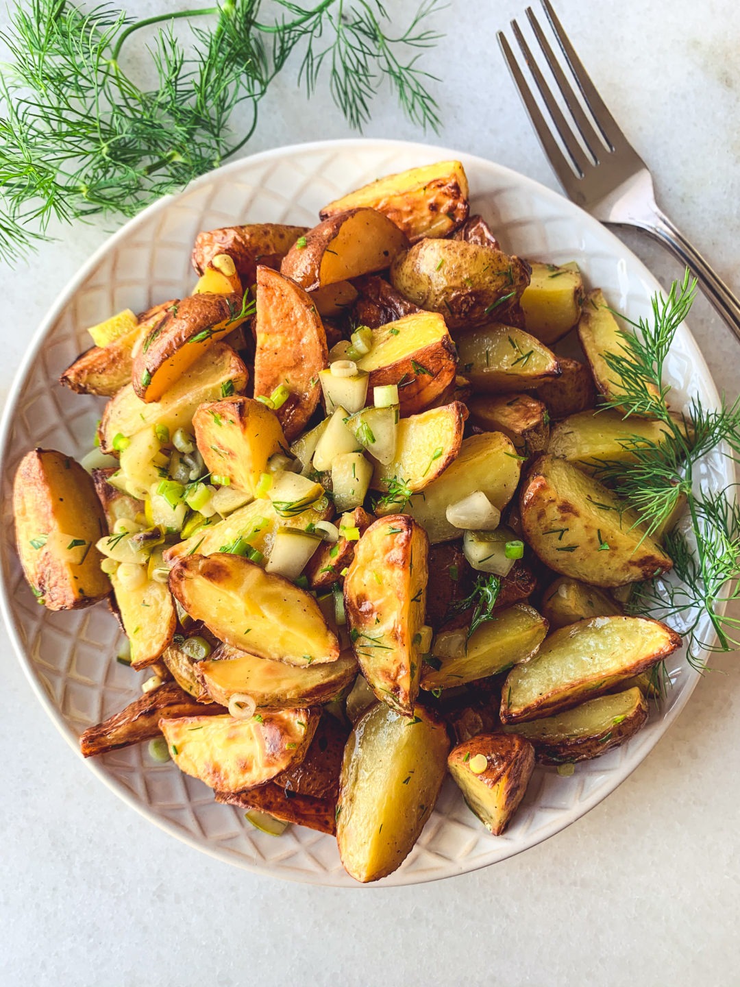 An overhead view of a vegan potato salad made with a maple mustard viniagrette and garnished with fresh dill.