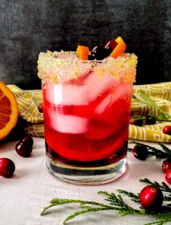 A bright pink mocktail featuring cranberries, fresh orange, and ginger beer.
